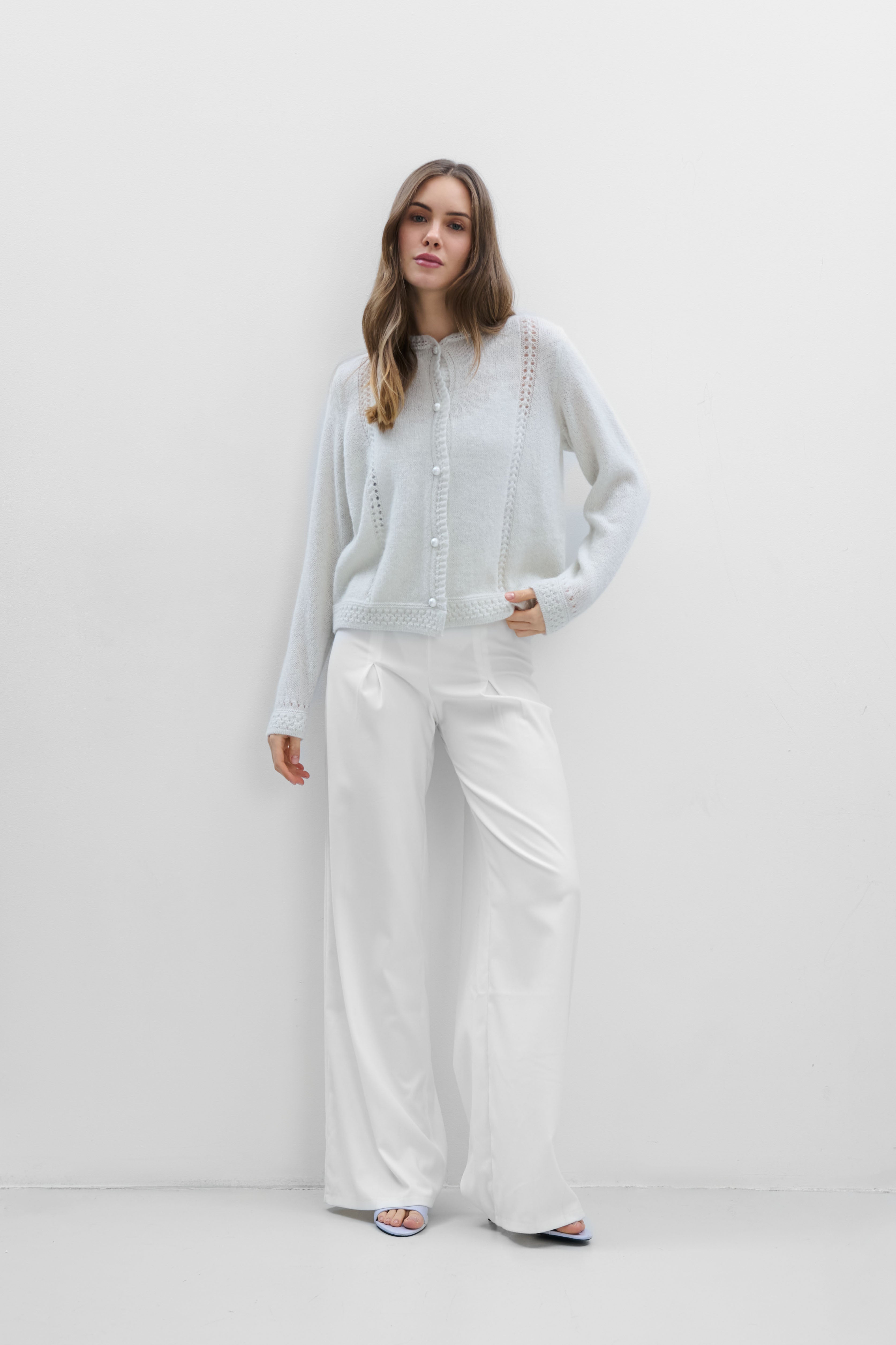 A delicate buttoned cardigan made of ecru alpaca wool and girl's wool.